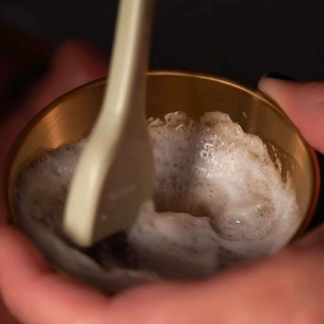 Cleansing foam prepared in a gold bowl for a Sanctuary scalp ritual